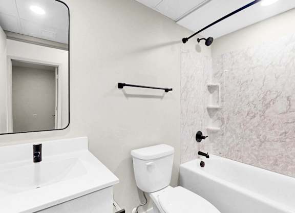 A white bathroom with a toilet, sink, and bathtub.
