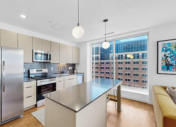 A modern kitchen with a stainless steel refrigerator and a large island.