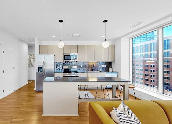 A modern kitchen with a yellow couch and a view of the city.
