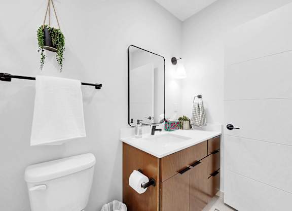 A white bathroom with a toilet, sink, and a mirror.