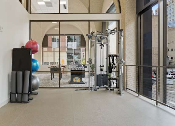 A gym with a variety of equipment including a treadmill, weights, and a bench.