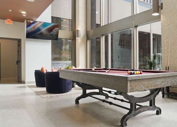 A pool table in a room with a plant on the side.