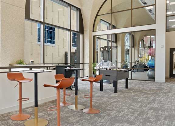 A room with a long table and orange chairs.