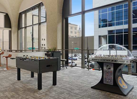 A foosball table is in the middle of a room with a pool table in the background.