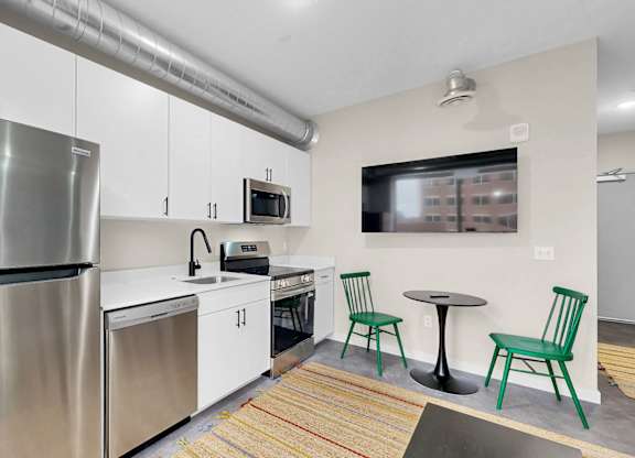 A modern kitchen with a stainless steel refrigerator and white cabinets.