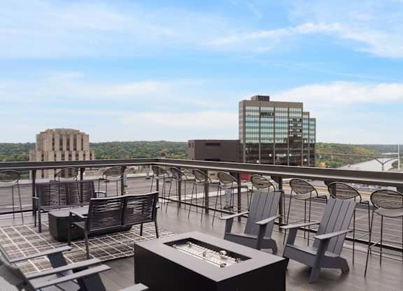 A rooftop patio with chairs and a table overlooking a cityscape.
