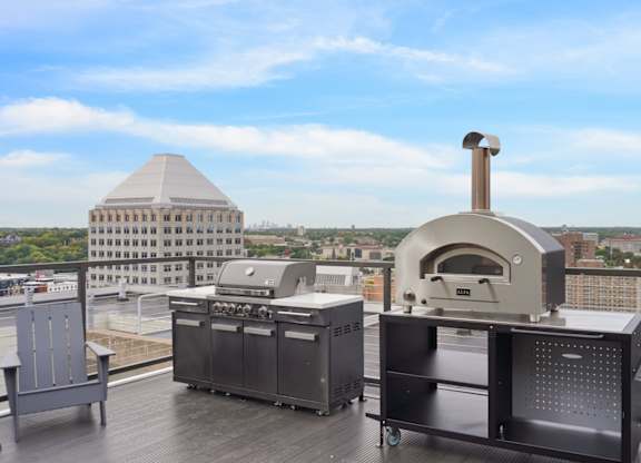 A pizza oven is on a balcony with a view of the city.