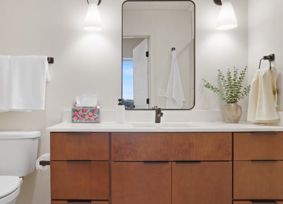 A bathroom with a toilet, sink, and mirror.