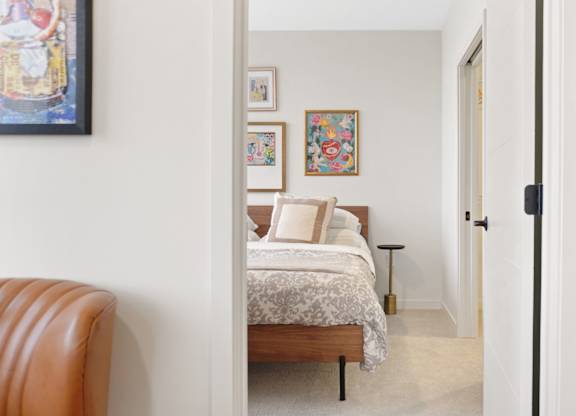 A bedroom with a bed, a chair, and pictures on the wall.