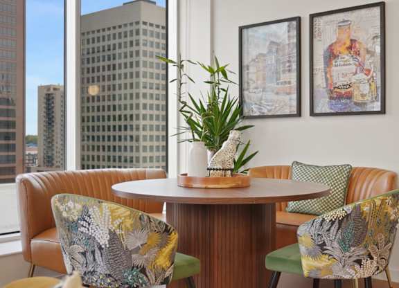 A round table with four chairs around it in a room with a city view.