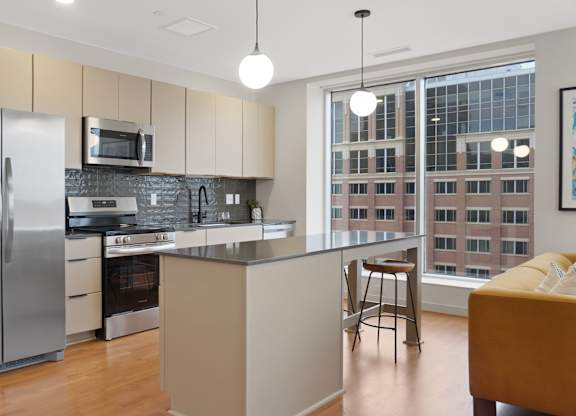 A modern kitchen with a refrigerator, microwave, oven, and sink.