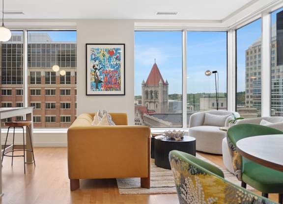 A living room with a yellow couch and a painting on the wall.
