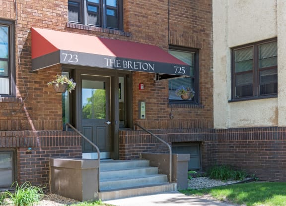 the front of a brick building with stairs and a red awning