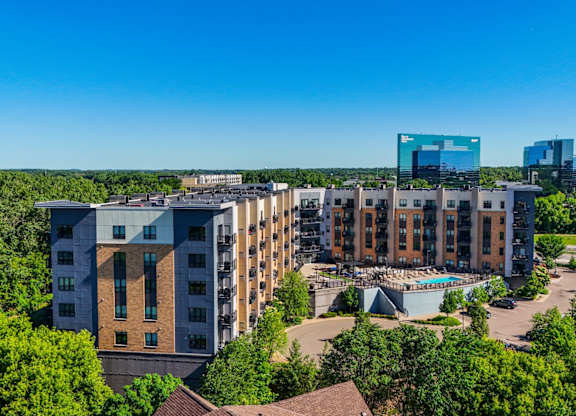 A large building complex surrounded by trees under a clear blue sky.