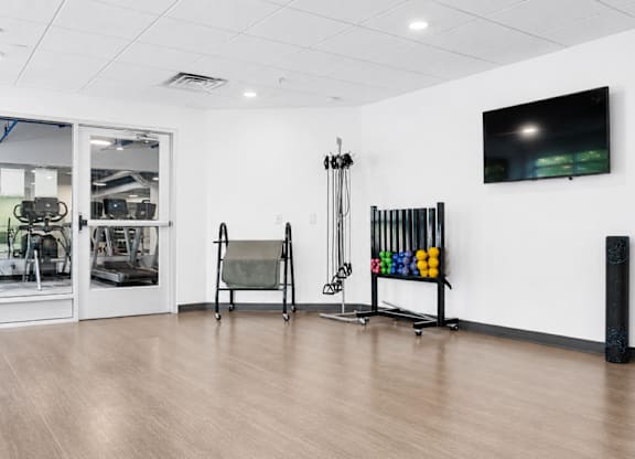 A gym with a variety of equipment including a bench press, a squat rack, and a rowing machine.