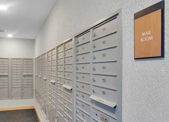 A mail room with a row of mailboxes and a sign on the wall.