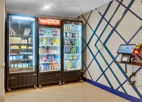 A small refrigerator with a glass door is filled with drinks and snacks.