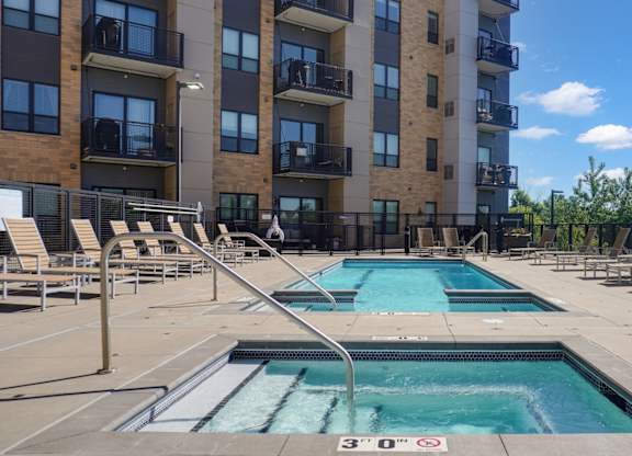 A swimming pool in front of a multi-story apartment building.