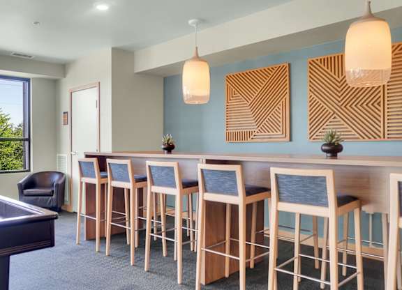 A room with a pool table and bar stools.