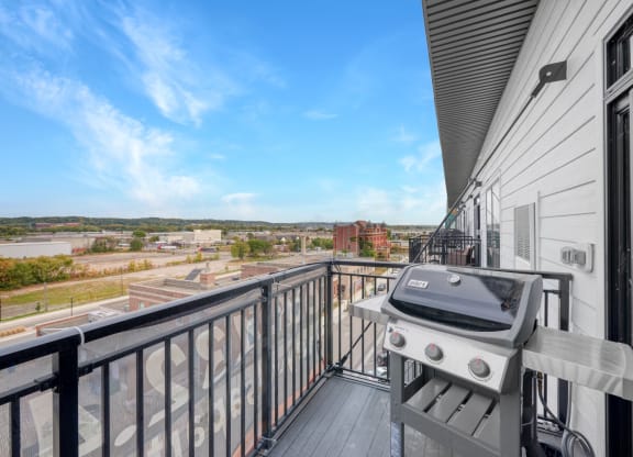 the balcony has a grill and a view of the city