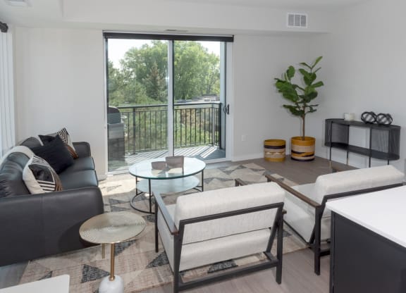 a living room with a sliding glass door that leads to a balcony at The Exchange Apartments, New Brighton Minnesota