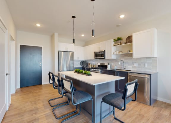 a kitchen with white cabinetry and a large island with a white countertop at The Exchange Apartments, New Brighton, 55112