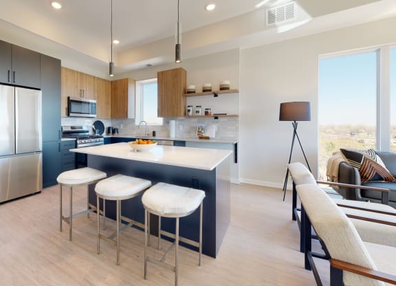 a kitchen with a large center island with three stools at The Exchange Apartments, Minnesota