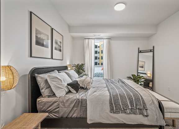 A bedroom with a large bed and a view of a city skyline.