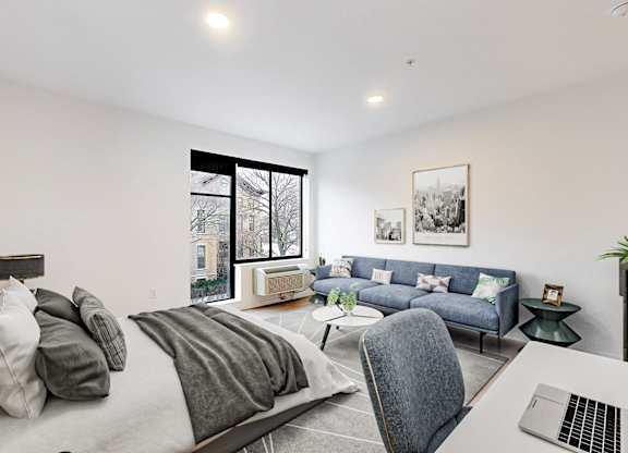 A modern bedroom with a large bed and a laptop on the desk.