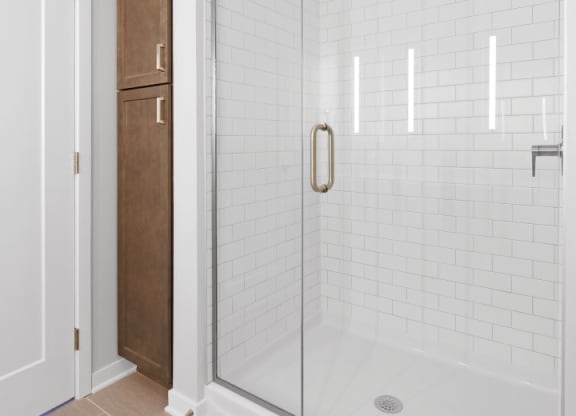 a bathroom with white tiles and a glass shower door