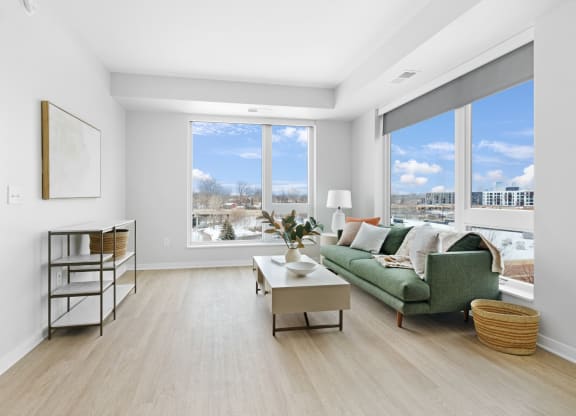 a living room with a green couch and large windows