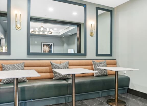 a seating area with two tables and two mirrors