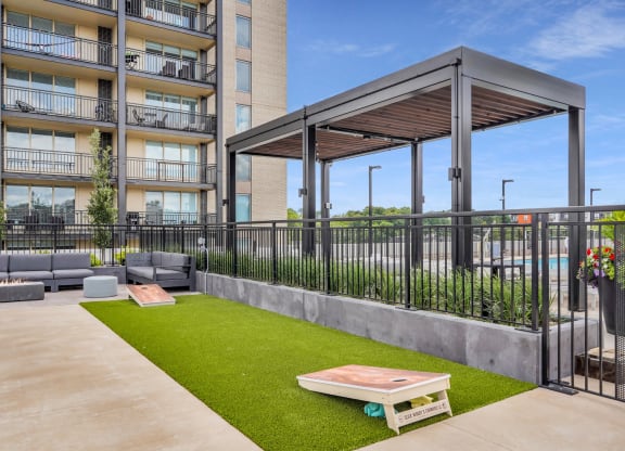 a patio with a table and chairs and a pergola in front of an apartment building
