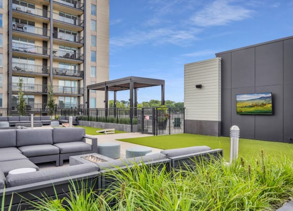 a grassy area with couches and a fire pit in front of an apartment building