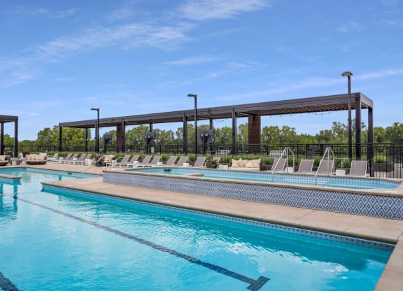 a swimming pool with chaise lounge chairs and trees in the background