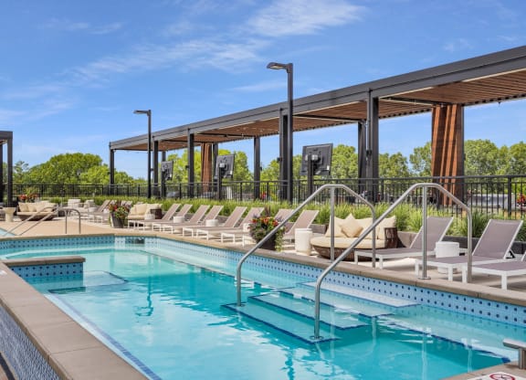 a resort style pool with lounge chairs and a pergola