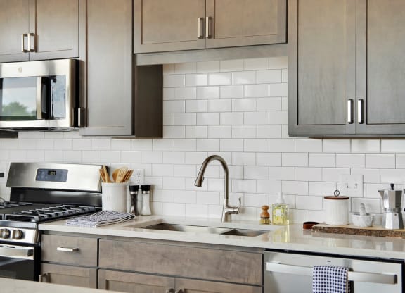 a kitchen with gray cabinets and white tile