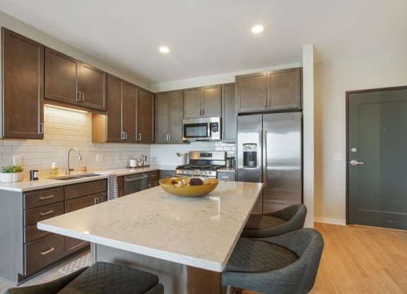 a kitchen with dark wood cabinets and a white island with a wooden bowl on top of it