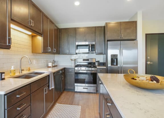 a kitchen with dark wood cabinets and white countertops