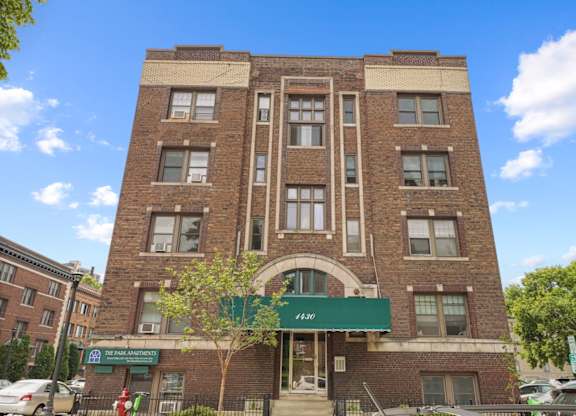 A large brick building with a green awning and a sign that reads