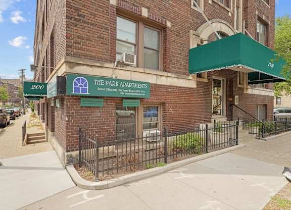 The front of a brick building with a green awning and a sign that says