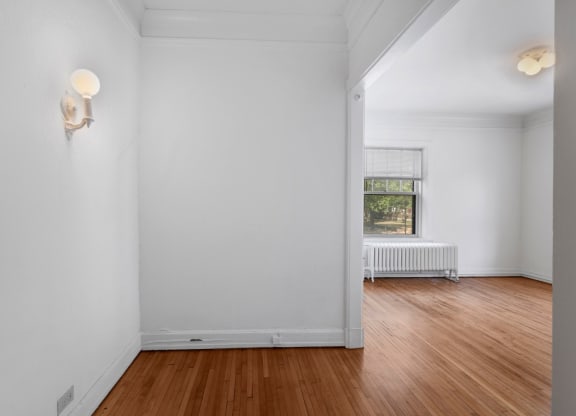 a bedroom with white walls and hardwood floors