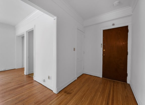 a bedroom with hardwood floors and white walls