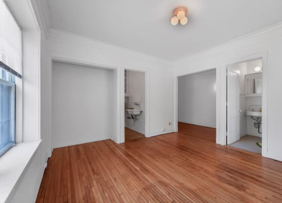 a bedroom with a hardwood floor and white walls