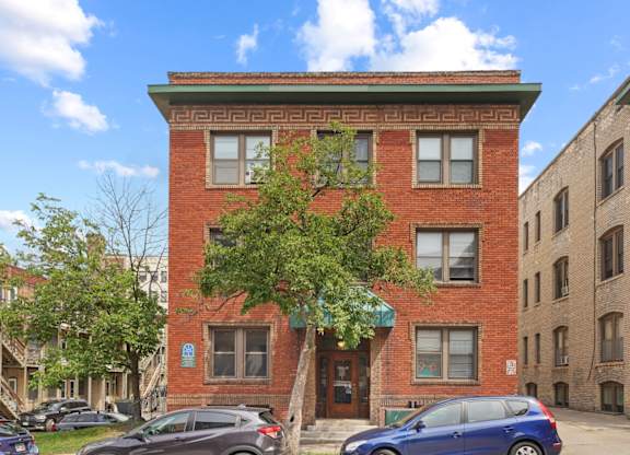 A red brick building with a tree in front of it.