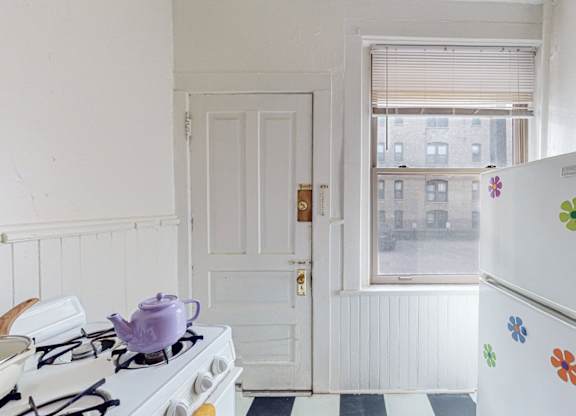 A white fridge with flower decals sits in a kitchen next to a stove.