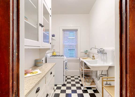 A kitchen with a checkered floor and white cabinets.