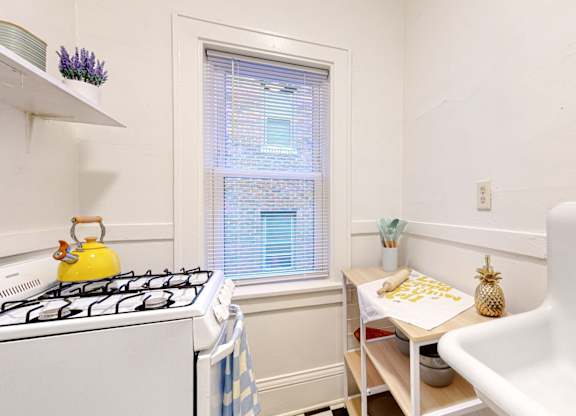 A small kitchen with a yellow gas stove and a white sink.