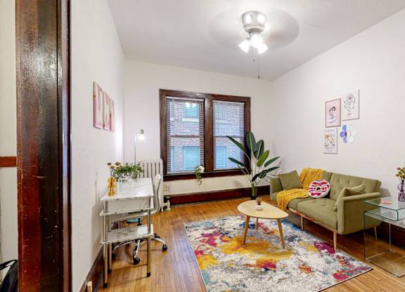 A living room with a green couch, a table, and a rug.