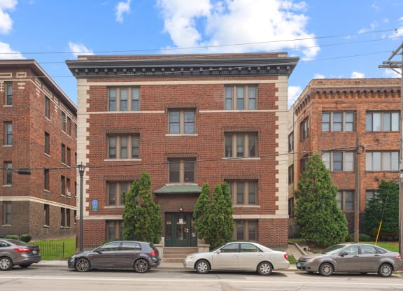 a red brick building with a black awning and cars parked in front of it